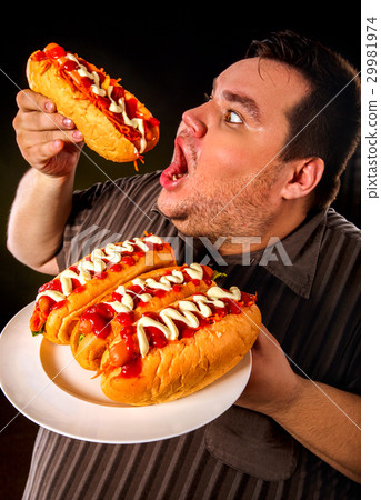 图库照片: fat man eating fast food hot dog. breakfast for