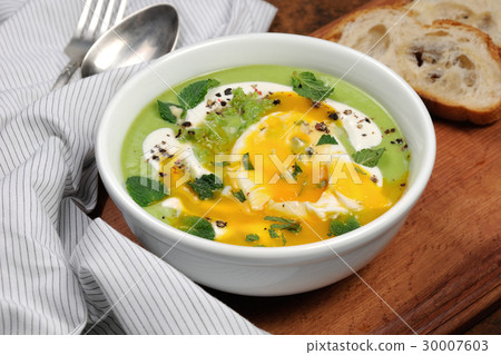 图库照片: pea puree soup with poached egg and peppermint