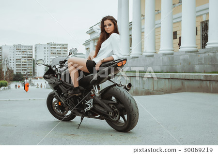 图库照片: biker girl rides a motorcycle in the rain. first