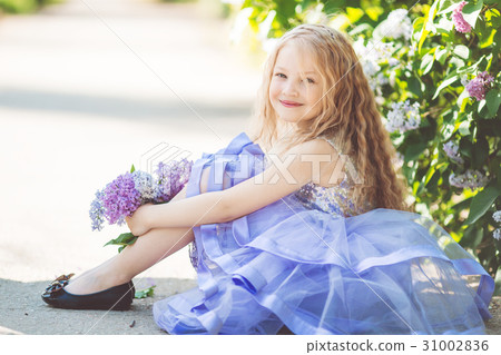 图库照片: beautiful child girl with bouquet of lilac flowers
