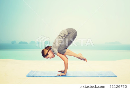 图库照片: woman making yoga in crane pose on mat