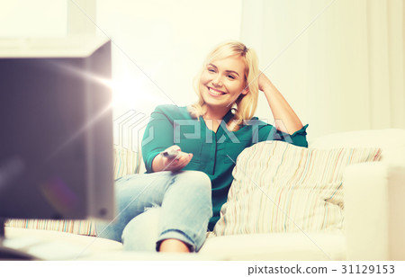图库照片: smiling woman with remote watching tv at home