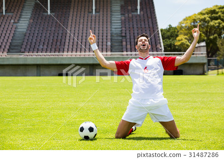 图库照片: excited football player kneeling in stadium