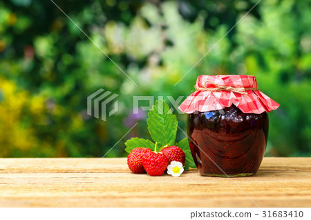 图库照片: strawberry jam in jar on table