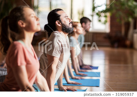 图库照片: group of people doing yoga dog pose at studio