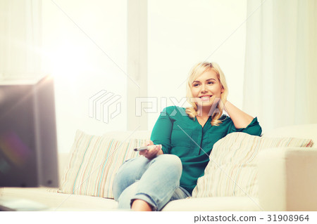 watching,seeingwatching 图库照片: smiling woman with remote watching tv at home