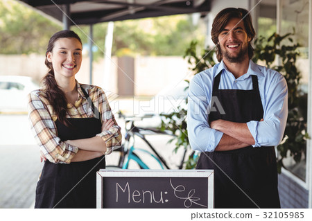 waiter and waitress standing with menu board outside the cafe