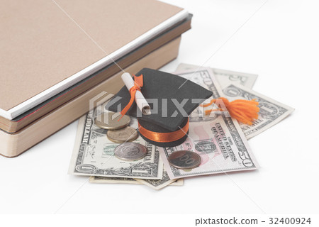 图库照片: graduation hat with money, book on white table.