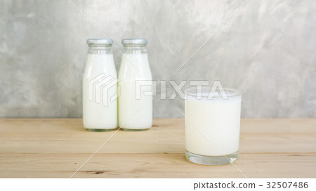 图库照片: a bottle and glass of milk on a wooden table.