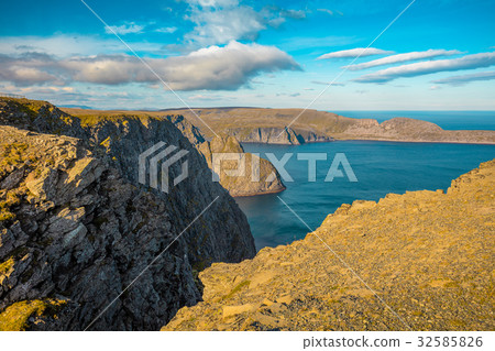 图库照片: rocky sea shore with blue cloudy sky