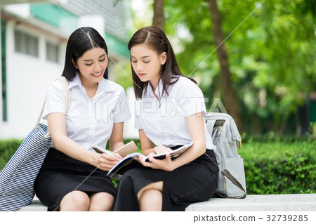 图库照片: two college students are discussing something on books