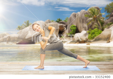 图库照片: woman doing yoga side angle pose on beach