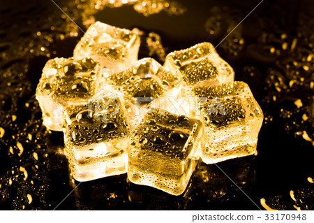 图库照片: ice cubes and water drop on light golden.