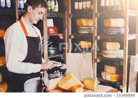 图库照片: male cheese shop assistant swipe credit card