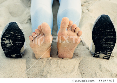 图库照片: bare female feet on the sand next to the shoes