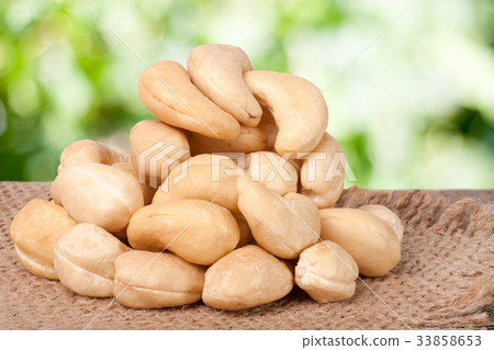 图库照片: heap of cashew nuts on a wooden table with sacking