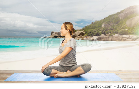 图库照片: woman doing yoga in twist pose on beach