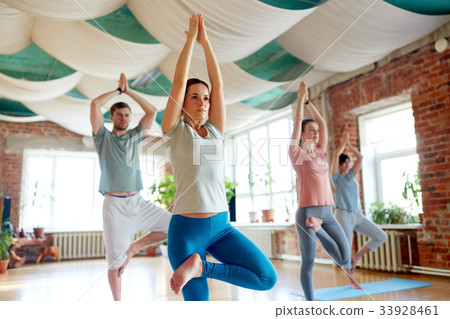 图库照片: group of people doing yoga tree pose at studio