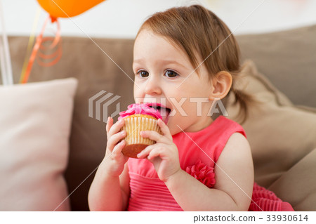 图库照片: happy baby girl eating cupcake on birthday party