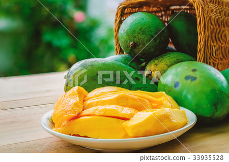 图库照片: ripe mango fruit in the basket on wooden table