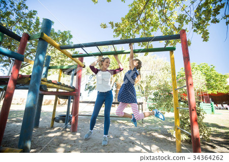 图库照片: happy mother talking to daughter hanging on jungle gym