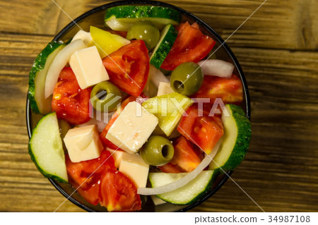 图库照片: greek salad in glass bowl on wooden table
