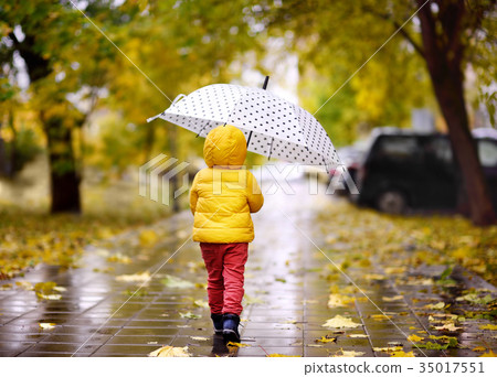 图库照片: little child walking in the city park at rainy autumn