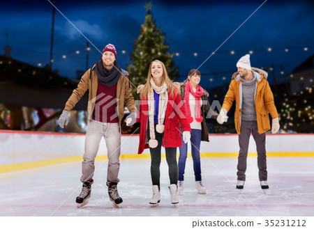 图库照片: happy friends on christmas skating rink