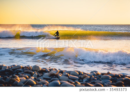 图库照片: surfer on the ocean wave at sunset or sunrise.