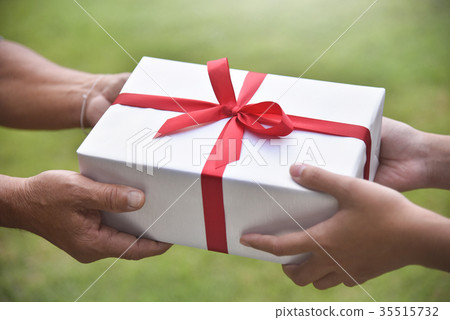 图库照片: asian woman giving a white gift box to elderly man