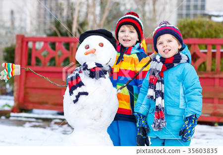 图库照片: two little siblings boys making a snowman