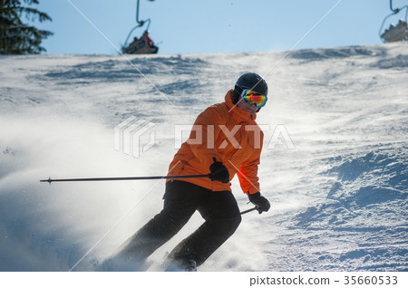 图库照片: male skier skiing downhill at ski resort against ski