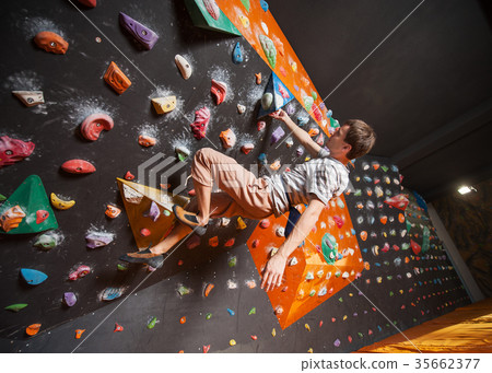 图库照片 strong male climber on boulder climbing wall indoor