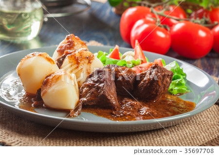 图库照片: pork meat stew served with potatoes and vegetables