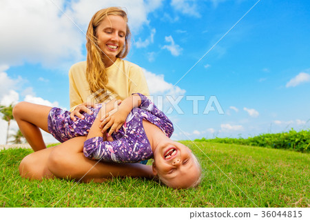 图库照片: mother tickling funny baby son lying on her laps