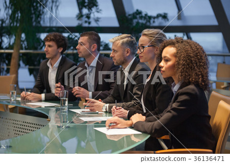 图库照片: a group of business people sit at a table in a