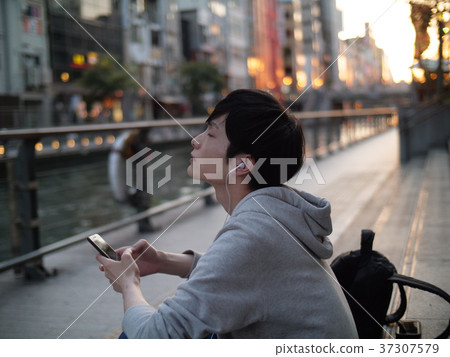照片素材(图片): 一个人在智能手机上听音乐