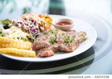 图库照片: pork chop steak with salad and gravy sauce in dish