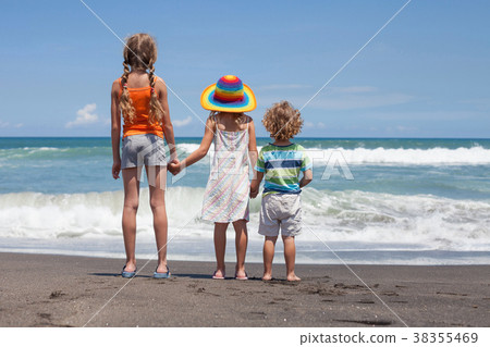 图库照片: three happy children playing on the beach at the day