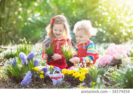 图库照片: kids plant and water flowers in spring garden