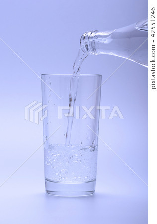 图库照片: mineral cold water pouring into glass from bottle