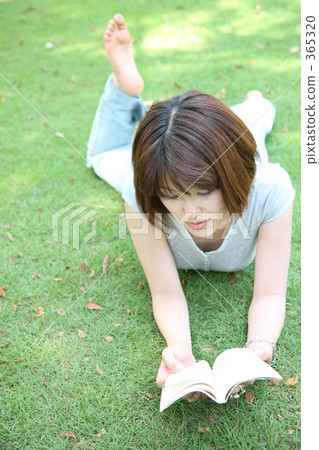 A woman reading a book on the lawn 365320