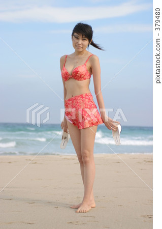 A swimsuit woman standing on a white sand beach 379480