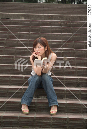 A woman reading a book on the stairs 04 417089