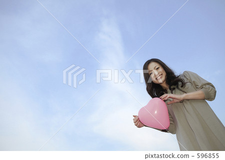 A woman smiling with a heart balloon A woman smiling with a heart balloon 596855