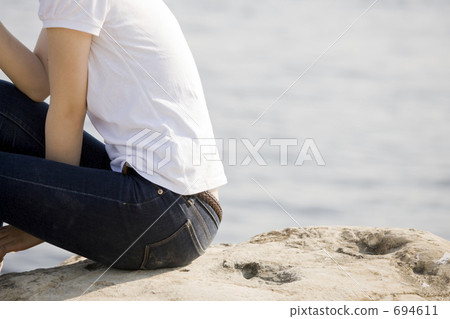 一個女人坐在沙灘上 694611
