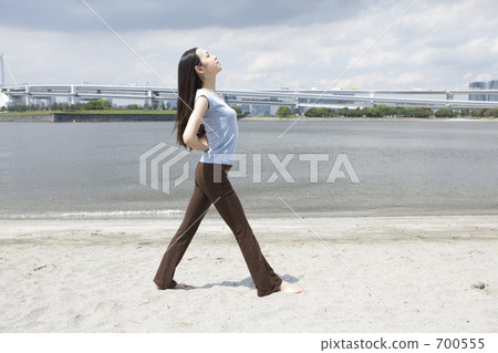 A woman who plays yoga at a sandy beach 700555