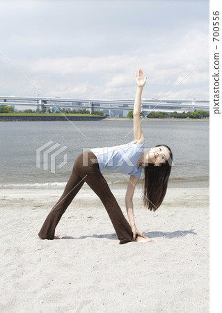 A woman who plays yoga at a sandy beach 700556