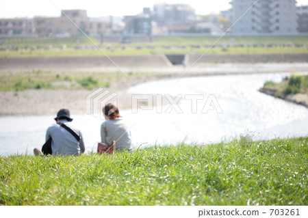 A couple sitting on the bank of the Tamagawa river 703261