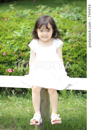 有一張微笑的面孔的一個女孩坐長凳 744454